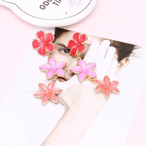 Detailed close-up of colorful three-tier floral drop earrings with vibrant enamel finish