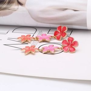 Detailed macro view of tiered colorful enamel flower drop earrings with golden metal edges