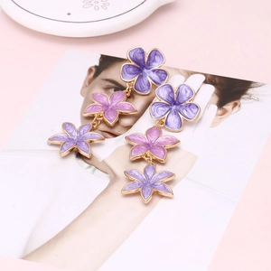 Macro shot of long floral drop earrings with purple and pink enamel layered petals