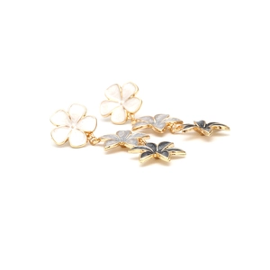 Detail of gradient enamel flower drop earrings featuring white, grey, and navy petals