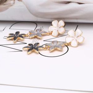Macro detail of cascading three-flower earrings with white and grey enamel petals