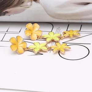 Macro shot of colorful enamel floral drop earrings on a minimalist white magazine layout