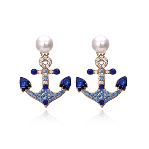 Golden anchor earrings with blue rhinestones and white pearls on white background