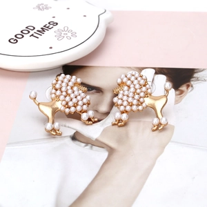 Elegant gold-tone poodle stud earrings with white pearl inlay in a luxury lifestyle setting