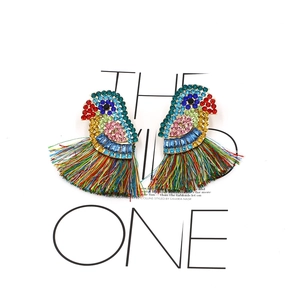 Détail de boucles d'oreilles perroquet en strass avec des pompons arc-en-ciel vifs