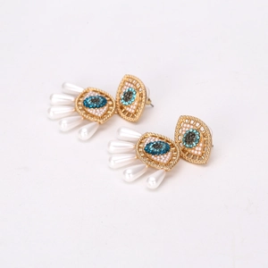 Exaggerated evil eye earrings with blue rhinestones and teardrop pearl fringes in gold