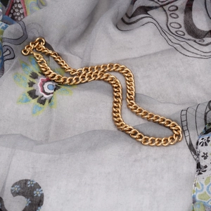 Detaillierte Flachbildansicht einer goldenen Gliederkette auf Vintage-Mustergewebe