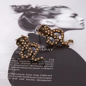 Vintage cobra earrings set with amber rhinestones on a stylish fashion magazine background