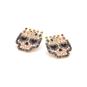 Macro shot of gold baroque skull earrings with pearls and colorful crown details