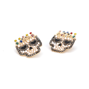 Macro detail of skull earrings featuring pearl inlay and colorful rhinestone crown
