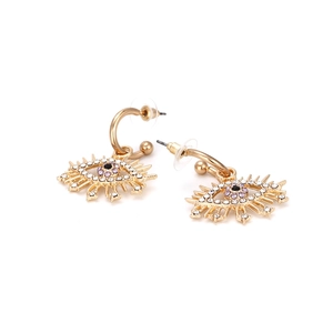 Détail de boucles d'oreilles œil porte-bonheur avec strass violets et cils dorés