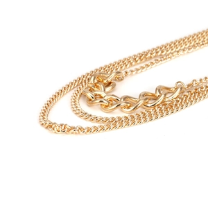 Detail of layered gold chunky chain necklace showing interwoven horseshoe link texture