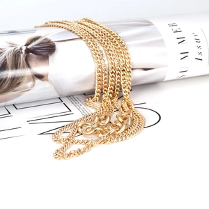 Layered gold link necklace with chunky polished metal rings on a fashion magazine