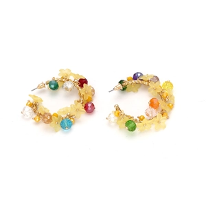 Dettaglio di orecchini a cerchio con fiori fatti a mano, perle di cristallo e chiusura oro