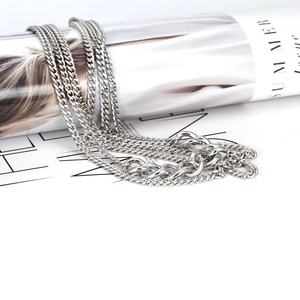 Silver cuban link chain necklace on a white background with a fashion magazine
