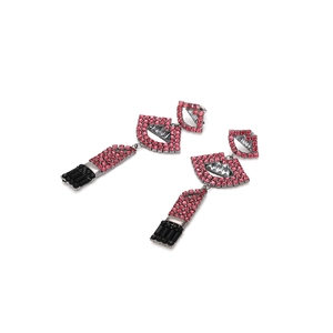 Détail de boucles d'oreilles longues rouge à lèvres ornées de strass roses et noirs