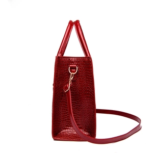 Side view of red crocodile pattern tote bag with glossy finish and gold hardware details