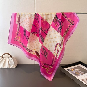 Elegant pink and white chain print silk square scarf hanging on a metal rack