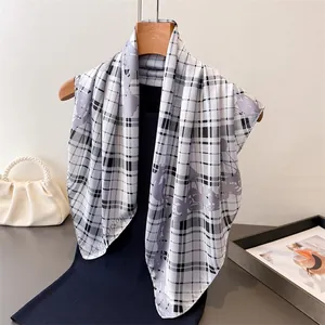 Detail of plaid silk scarf with chain print displayed on a wooden hanger with accessories