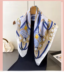 Detailed shot of a silk-like square scarf featuring golden chain and heart prints