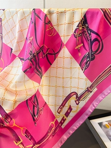 Close-up of silk scarf with equestrian chain print and elegant pink draping details