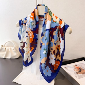Seidenschal mit Blumenmuster in Blau und Orange elegant drapiert auf einer Weste
