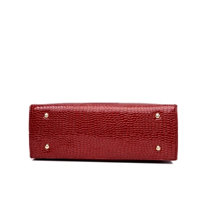 Red crocodile pattern tote bag with protective gold metal studs on the bottom