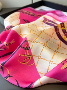 Detailed close-up of luxury silk scarf featuring equestrian chain print and satin luster