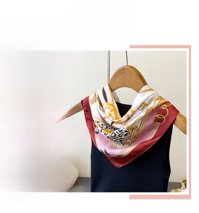 Detail of silk satin scarf featuring chain prints and leopard patterns in pink and gold