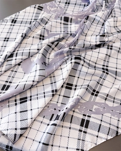 Detailed close-up of plaid silk scarf with lavender animal print and smooth texture