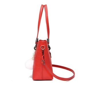 Red crocodile pattern bucket bag with white pompom pendant and adjustable strap