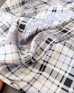 Macro shot of plaid silk-like scarf showing soft texture and luxury chain print