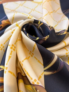 Detail of luxury silk scarf showing chain print and smooth satin texture in navy and beige