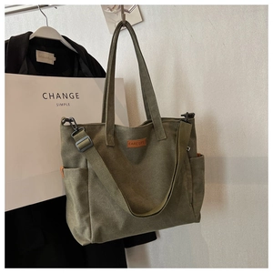 Detail of army green canvas tote bag with webbed handles and detachable shoulder strap