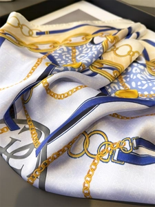 Detail of silk scarf featuring gold chains and blue leopard print with glossy texture