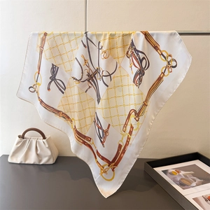 Detailed macro view of silk satin square scarf featuring equestrian chain and leather prints