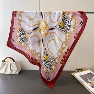 Detailed shot of silk scarf featuring chain print, leopard patterns and gold heart charms