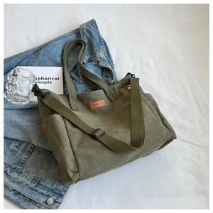 Detailed view of olive green canvas tote bag featuring leather label on denim jacket