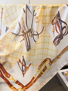 Detail of luxury silk scarf with chain print and equestrian motif showing smooth fabric texture