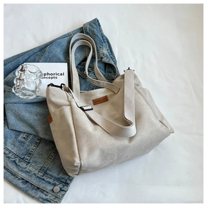 Close-up of beige canvas tote bag with brown leather patch and adjustable shoulder strap