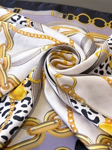 Detailed macro shot of silk square scarf featuring gold chain and leopard print patterns