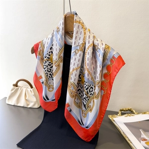 Detailed close-up of chain print silk scarf with leopard patterns and red hand-rolled edges