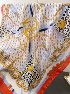 Macro shot of chain print silk scarf with golden heart motifs and leopard pattern details