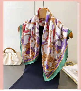 Detail of vintage chain print silk scarf with green borders hanging on a wooden hanger