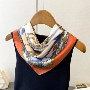 Detail of silk scarf with vintage chain patterns and orange borders on a black top