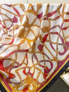 Close-up of silk scarf showing vintage gold chain patterns and smooth satin texture
