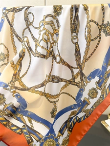 Detail of silk square scarf featuring equestrian chain print and orange border