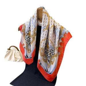 Elegant silk-feel scarf with red and blue chain print displayed on a mannequin