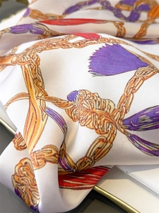 Detailed macro view of vintage silk scarf with golden chains and purple tassel patterns