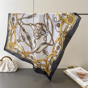 Close-up of luxury baroque silk scarf featuring golden chain patterns and black borders